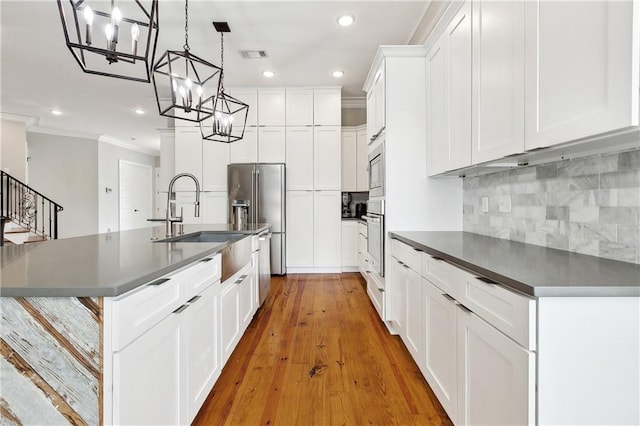kitchen with dark countertops, a notable chandelier, stainless steel appliances, recessed lighting, and ornamental molding