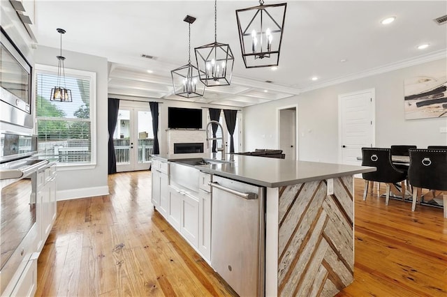 kitchen with a sink, white cabinets, light wood-type flooring, and a chandelier