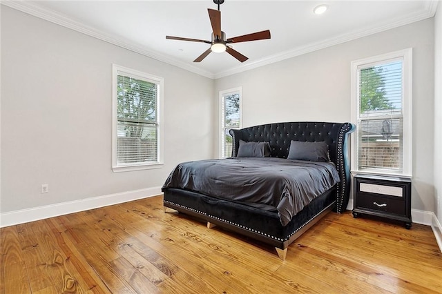 bedroom with baseboards, multiple windows, ornamental molding, and light wood-style floors