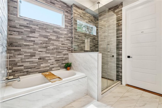 bathroom with marble finish floor, a bath, and a shower stall