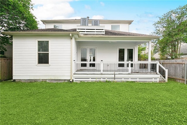back of property featuring french doors, roof with shingles, a deck, a fenced backyard, and a yard