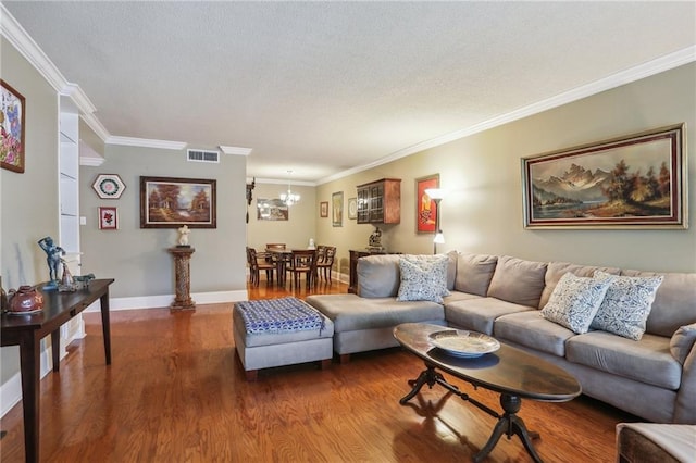 living room featuring an inviting chandelier, a textured ceiling, wood finished floors, visible vents, and ornamental molding