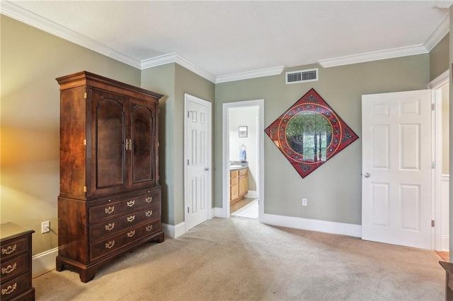 bedroom featuring visible vents, baseboards, ornamental molding, ensuite bathroom, and light carpet