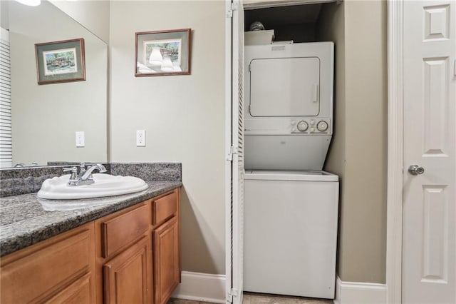 bathroom with stacked washer and dryer, baseboards, and vanity