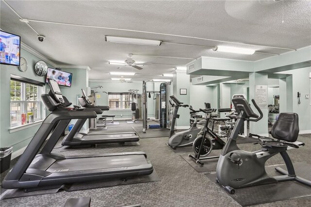 gym with plenty of natural light, a textured ceiling, crown molding, and baseboards