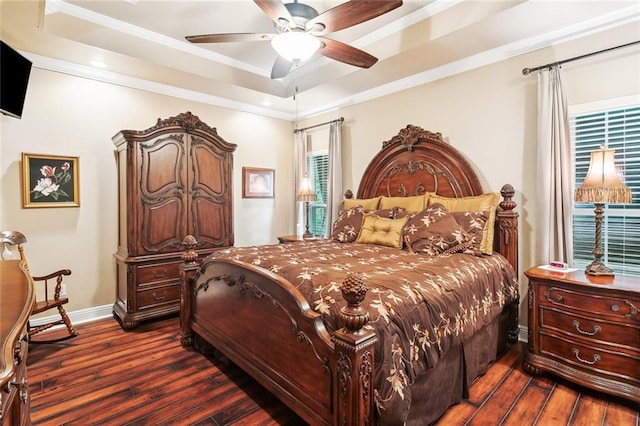 bedroom with crown molding, baseboards, dark wood-style floors, a tray ceiling, and a ceiling fan