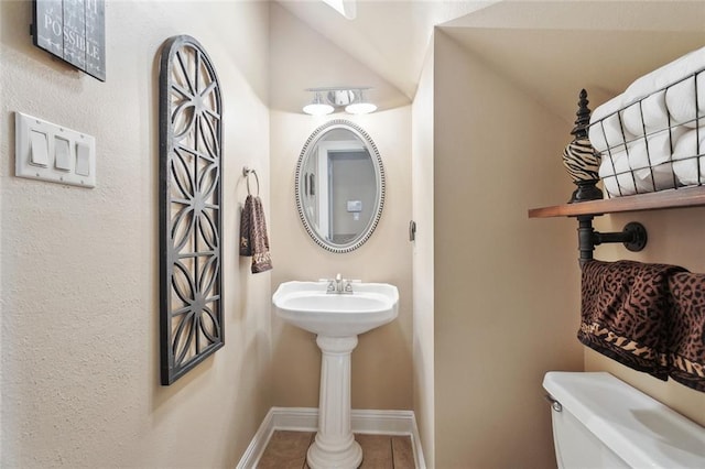 half bath featuring toilet, tile patterned floors, and baseboards