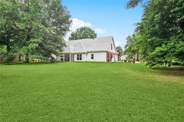 rear view of property with a yard and metal roof