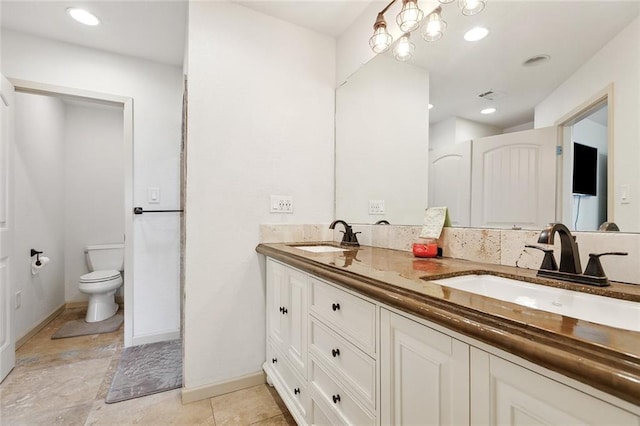 8752 Leisure Dr, Denham Springs, LA 70726 - full bathroom with double vanity, toilet, baseboards, and a sink
