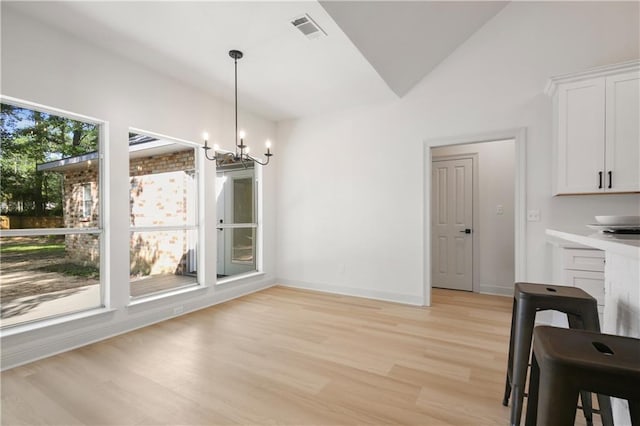 unfurnished dining area with visible vents, lofted ceiling, baseboards, light wood-style flooring, and a notable chandelier