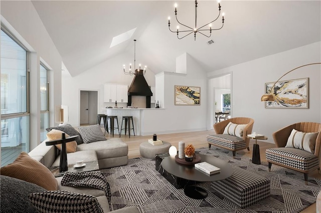 living area featuring a skylight, high vaulted ceiling, light wood-style flooring, and a chandelier