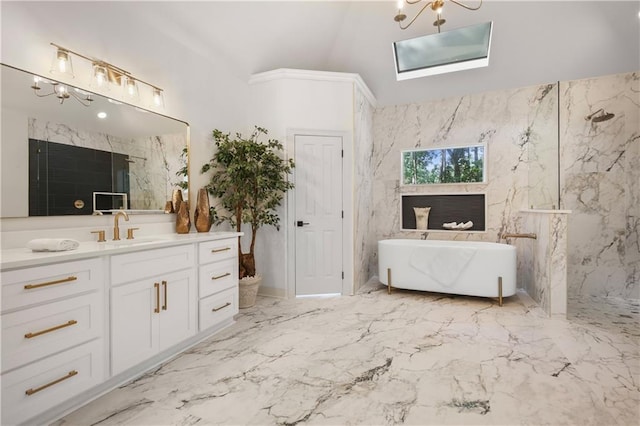 full bathroom with a freestanding tub, an inviting chandelier, marble finish floor, and vanity