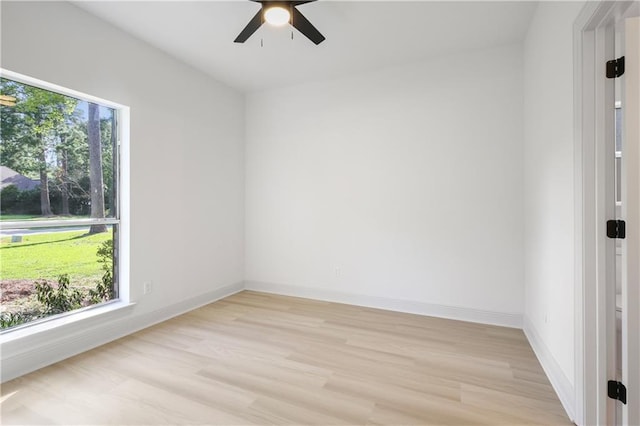 spare room with baseboards, a ceiling fan, light wood-style flooring, and a healthy amount of sunlight
