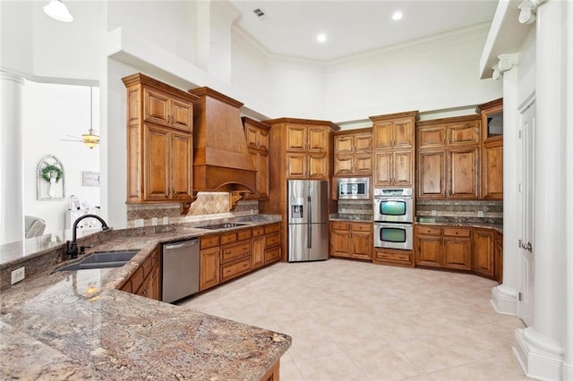 30222 N Dixie Ranch Rd, Lacombe, LA 70445 - kitchen featuring appliances with stainless steel finishes, brown cabinetry, premium range hood, a sink, and backsplash
