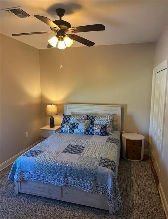 bedroom featuring visible vents, carpet floors, a closet, baseboards, and ceiling fan