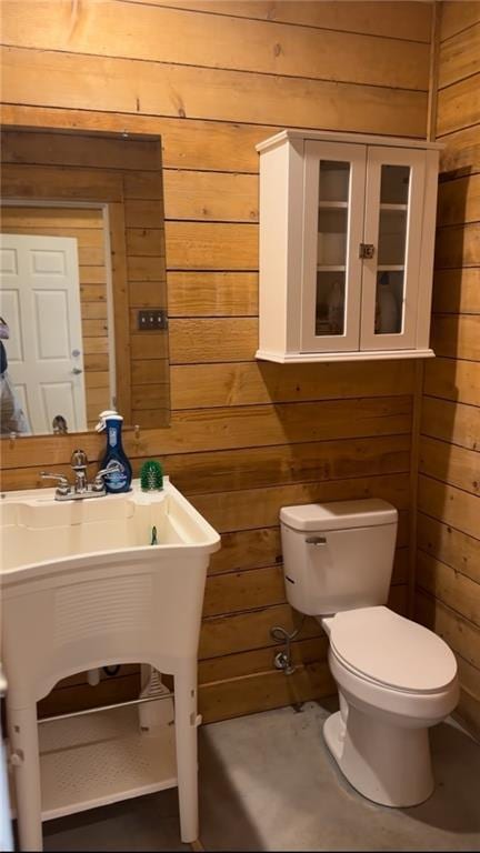 bathroom featuring toilet and wood walls