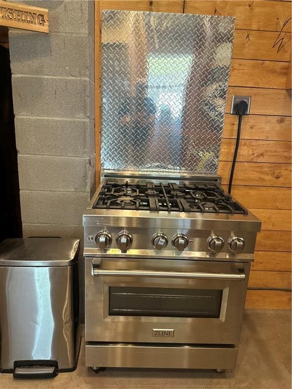 kitchen with high end stove, concrete floors, and tasteful backsplash