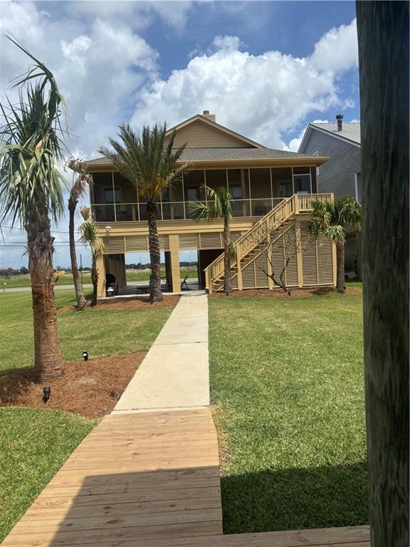 view of front of property featuring stairs, a sunroom, and a front lawn