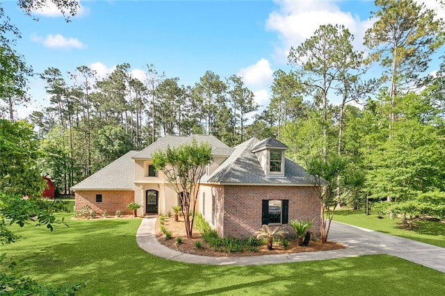 view of front facade with brick siding, driveway, and a front yard