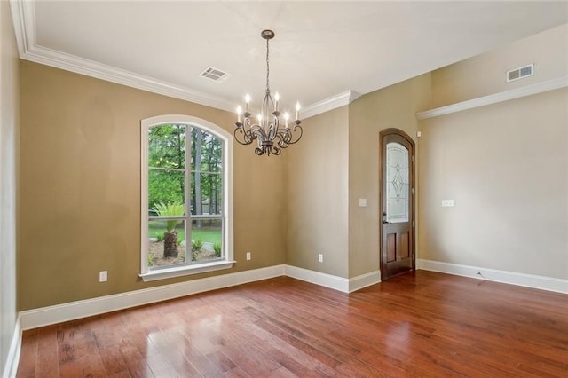 spare room featuring visible vents, ornamental molding, wood-type flooring, and a chandelier