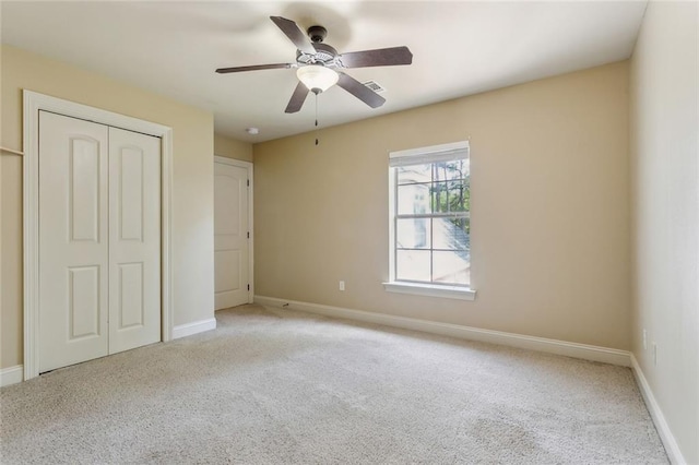 unfurnished bedroom featuring baseboards, ceiling fan, light carpet, and a closet