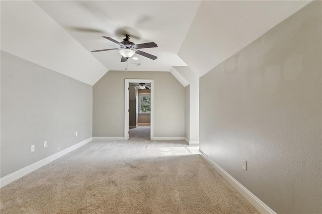 additional living space featuring light colored carpet, visible vents, a ceiling fan, baseboards, and vaulted ceiling