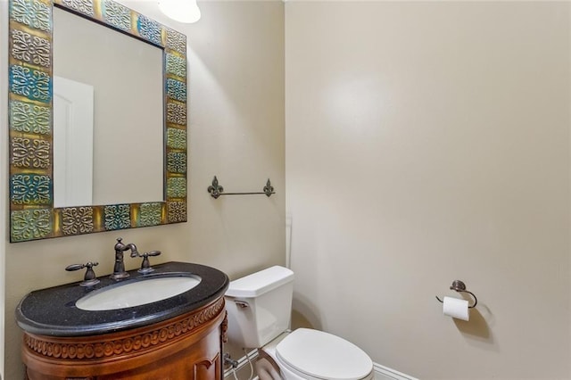 half bath featuring vanity, baseboards, and toilet