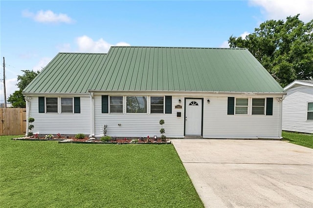view of front facade featuring fence, a front lawn, driveway, and metal roof