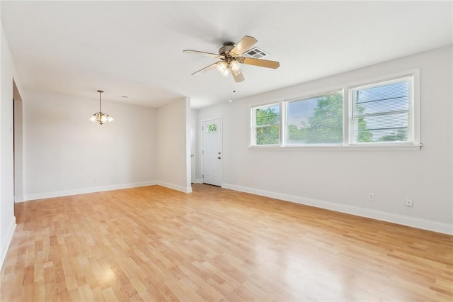 spare room featuring baseboards, visible vents, light wood finished floors, and ceiling fan with notable chandelier