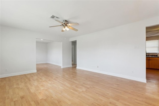 empty room with a ceiling fan, baseboards, visible vents, and light wood finished floors