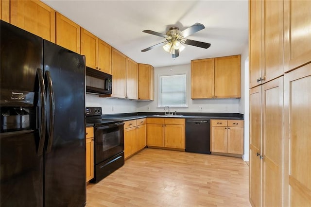 kitchen with dark countertops, ceiling fan, a sink, light wood finished floors, and black appliances