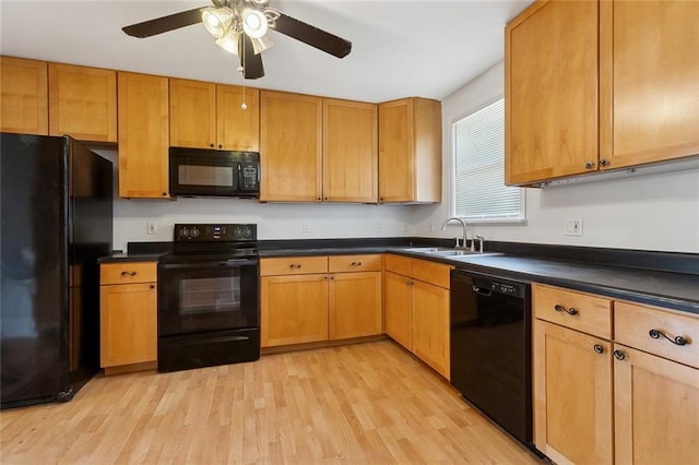 kitchen featuring a sink, dark countertops, black appliances, and light wood finished floors