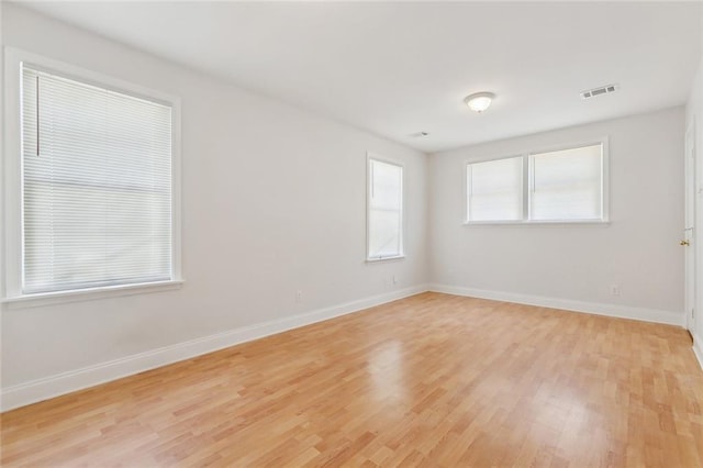 spare room with visible vents, baseboards, and light wood-type flooring