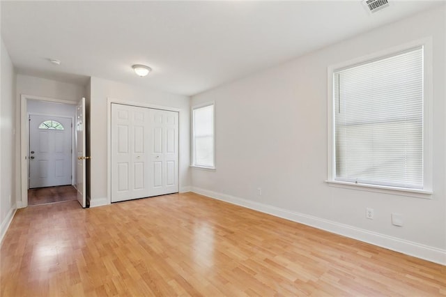 unfurnished bedroom featuring visible vents, light wood-style flooring, baseboards, and a closet