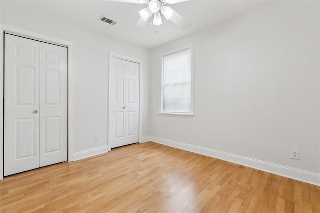 unfurnished bedroom with visible vents, multiple closets, baseboards, and light wood-type flooring