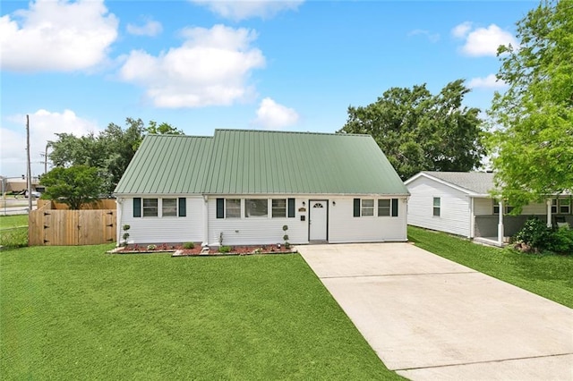 view of front facade with fence, a front lawn, concrete driveway, and metal roof