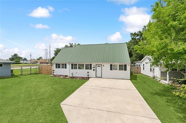 view of front of house with fence, metal roof, driveway, and a front lawn