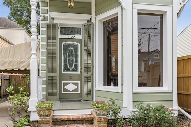 entrance to property with covered porch and fence