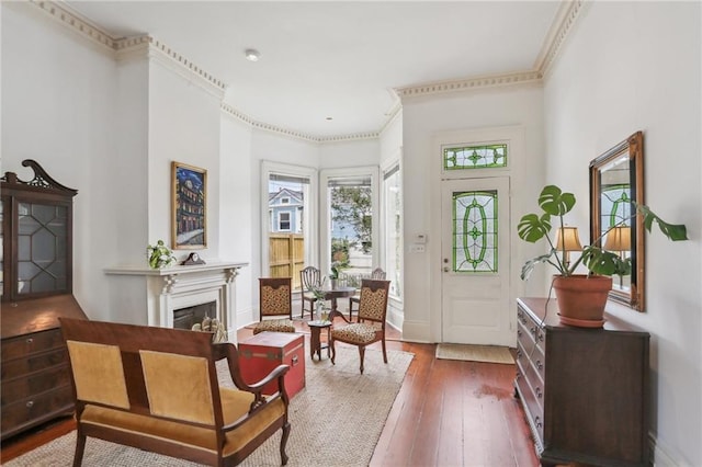 foyer entrance with baseboards, ornamental molding, a fireplace, and hardwood / wood-style flooring