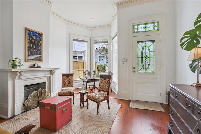 entrance foyer featuring dark wood-style flooring, ornamental molding, and a fireplace