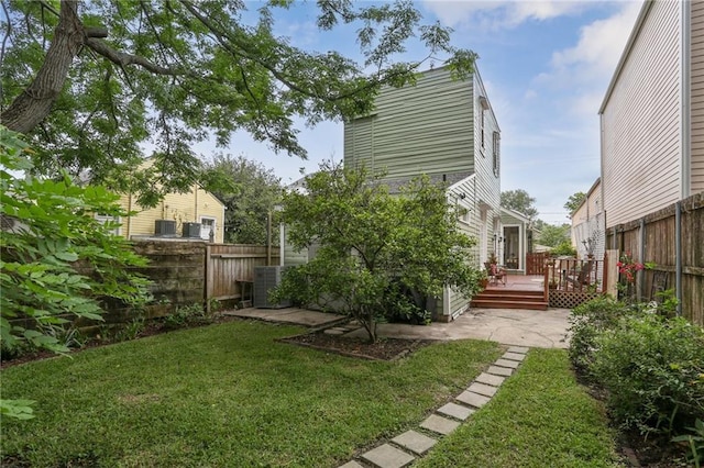 view of yard with a deck, central AC, and fence