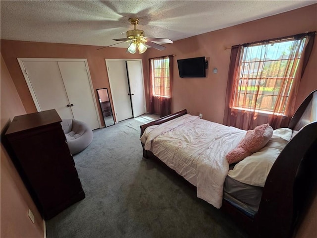 bedroom with ceiling fan, carpet, two closets, and a textured ceiling
