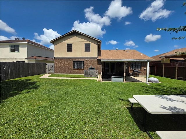 rear view of house featuring a lawn, a patio, a fenced backyard, and brick siding