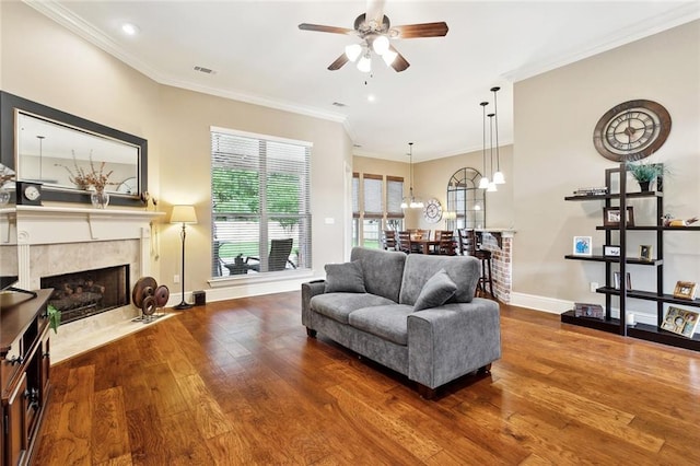 living area with visible vents, a fireplace, hardwood / wood-style floors, baseboards, and a ceiling fan