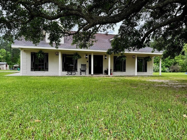 back of house featuring a yard, brick siding, and a shingled roof