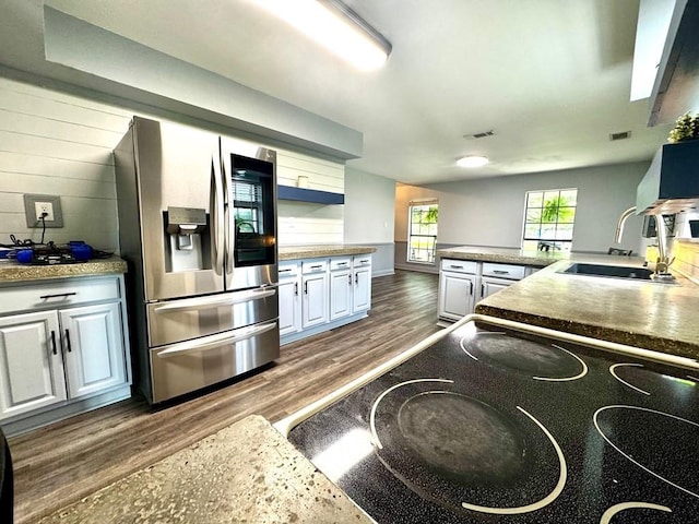 kitchen with white cabinets, a sink, stainless steel fridge with ice dispenser, dark wood-style floors, and stovetop
