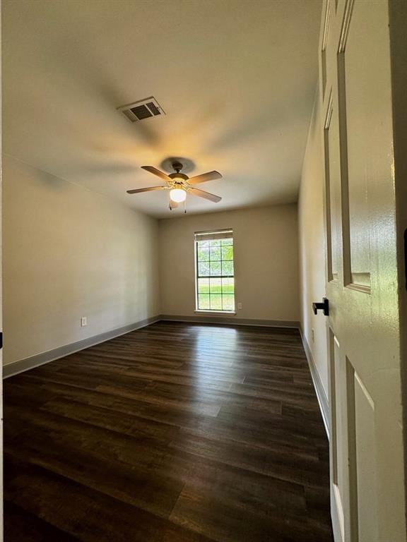 spare room featuring visible vents, a ceiling fan, baseboards, and dark wood-style floors
