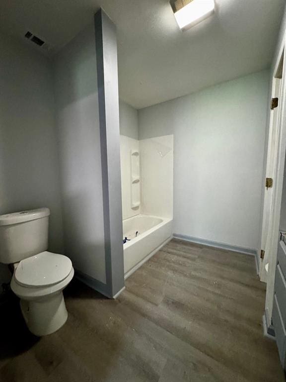 bathroom with shower / bathing tub combination, toilet, wood finished floors, and visible vents