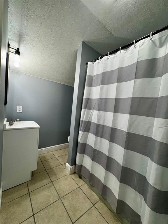 full bathroom featuring tile patterned flooring, vanity, toilet, a shower with shower curtain, and a textured ceiling