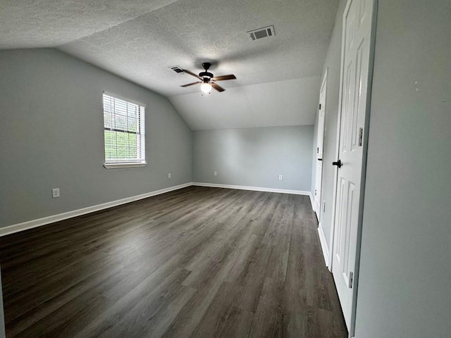 bonus room with a textured ceiling, ceiling fan, lofted ceiling, and dark wood-type flooring